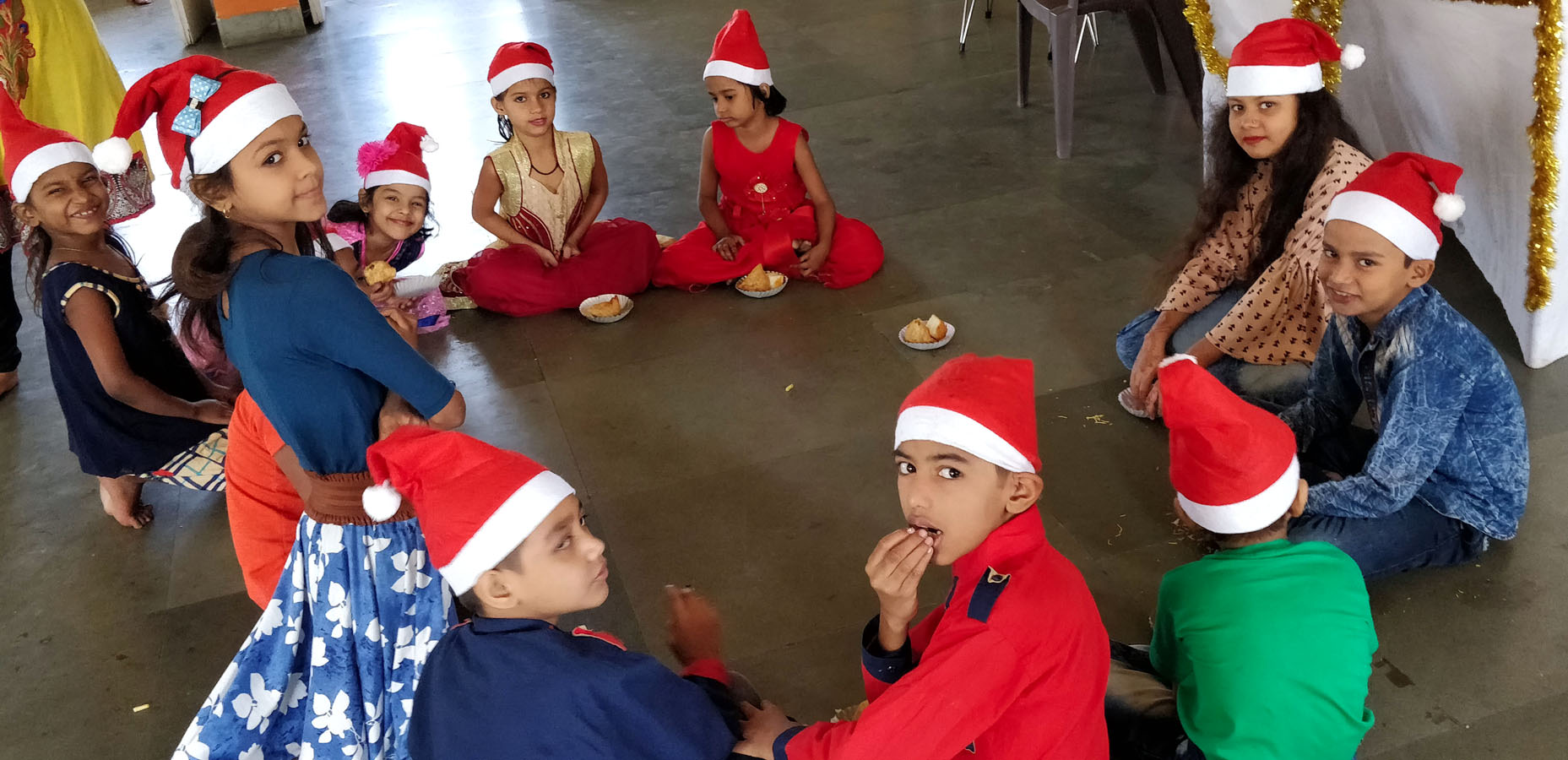 Cute little children in santa caps munching away on samosas and other snacks in the party