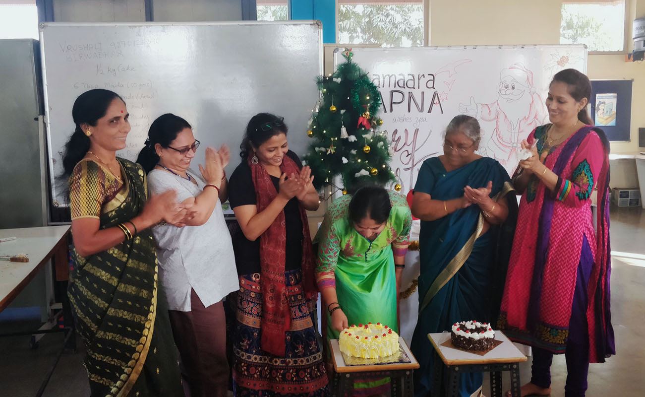 Teachers and staff watch as a student cuts one of the cakes made by Ms. Vrushali. What a sweet Christmas !