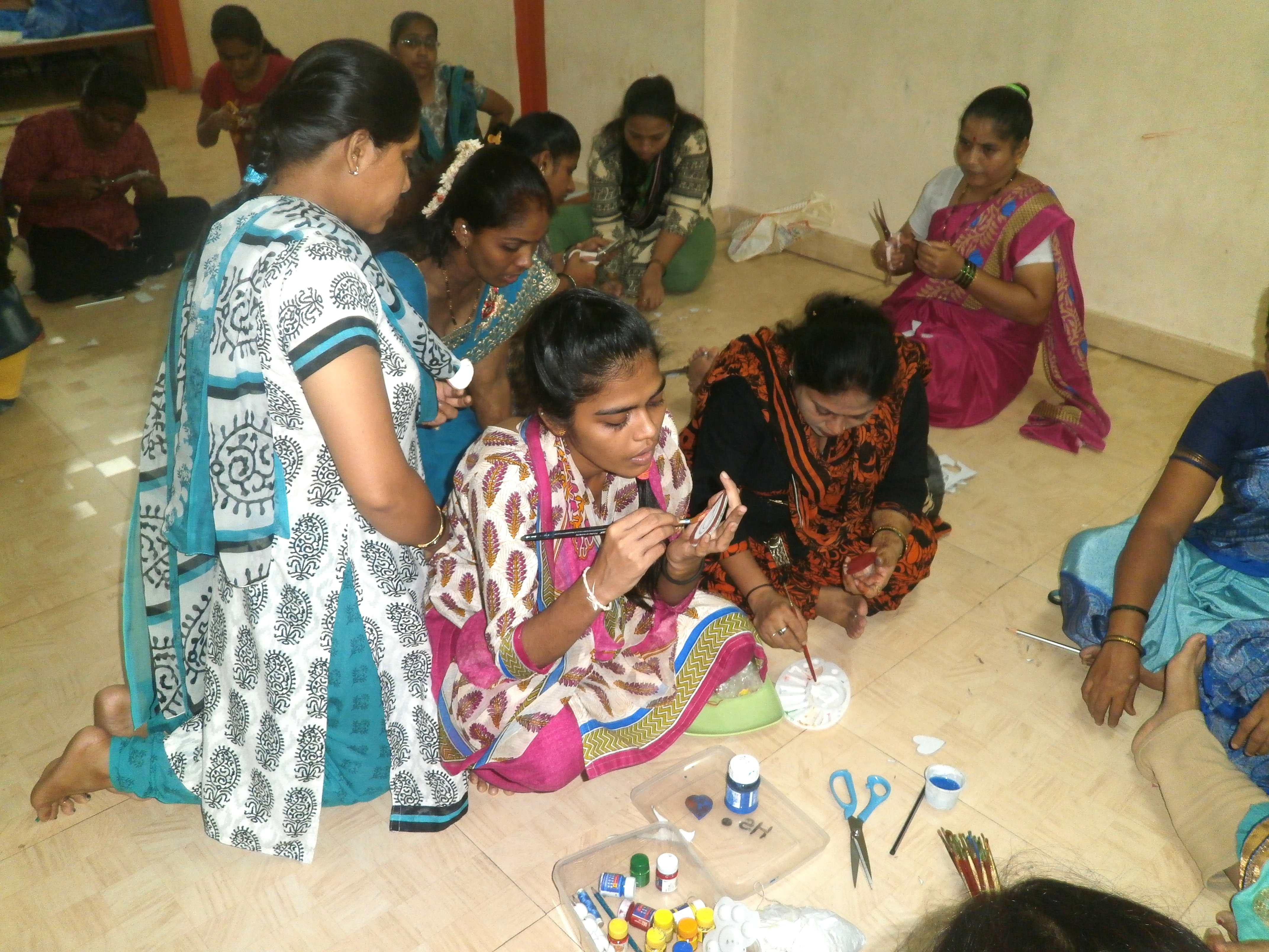 Women busy painting a puppet
