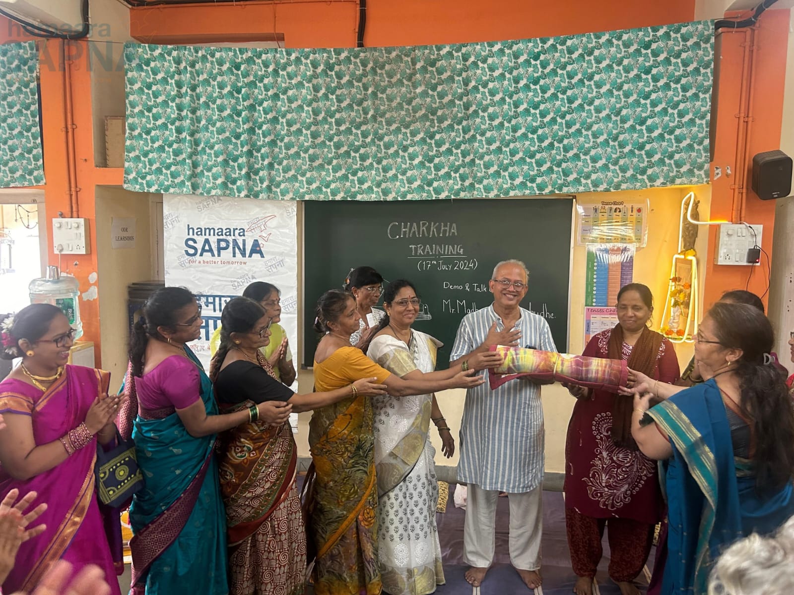 Women giving away a token of gratitude to Mr. Sahasrabudhe, a yoga mat made from Khadi by themselves